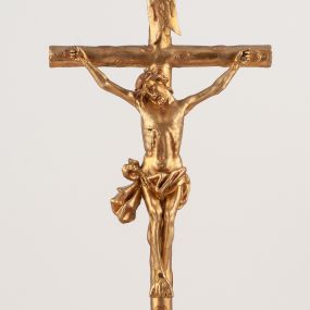 Zdjęcie nr 1: Grupa Ukrzyżowania umieszczona jest na wysokim cokole z ryzalitem pośrodku, profilowanym u dołu i zakończonym gzymsem z kostkowaniem. Do cokołu z trzech stron przytwierdzone są gwoździkami płaskorzeźbione narzędzia Męki Pańskiej. Grupa ustawiona jest na rzeźbionym podłożu imitującym skałę. Pośrodku znajduje się krzyż z pnia drzewa, do którego przybita jest trzema gwoździami figurka umarłego Chrystusa. Jego ciało jest w dużym zwisie, o ramionach przyjmujących kształt łuku półkolistego, głowa opada na prawy bark, nogi ułożone są równolegle, stopy skrzyżowane w układzie prawa na lewą. Twarz pociągła, okolona krótką brodą oraz silnie kręconymi włosami, na głowie korona cierniowa. Ciało smukłe, z podkreślonymi żebrami klatki piersiowej i zaznaczonymi śladami męki. Biodra przepasane krótkim, ekspresyjnie drapowanym perizonium, zawieszonym na podwójnym sznurze, odsłaniającym prawe biodro, zawiązanym na prawym boku. Pionowa belka krzyża zakończona banderolą z rytym napisem „IN / RI”. U podstawy krzyża znajduje się czaszka z piszczelami. 
Po prawej stronie krzyża stoi Maria ze splecionymi z przodu dłońmi. Ubrana jest w tunikę, przepasaną w talii oraz płaszcz narzucony na głowę i ramiona. Po lewej stronie znajduje się św. Jan. Zwrócony jest w trzech czwartych w prawo, klęczy na prawym kolanie i prawą dłoń kładzie na piersi, lewą rękę wyciąga do przodu. Jego twarz okalają długie włosy opadające na ramiona. Ubrany jest w tunikę, przepasaną w talii. 
Figury oraz detale rzeźbiarskie i profile cokołu pozłocone, struktura cokołu polichromowana na czarno. 