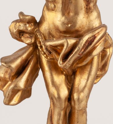 Zdjęcie nr 10: Grupa Ukrzyżowania umieszczona jest na wysokim cokole z ryzalitem pośrodku, profilowanym u dołu i zakończonym gzymsem z kostkowaniem. Do cokołu z trzech stron przytwierdzone są gwoździkami płaskorzeźbione narzędzia Męki Pańskiej. Grupa ustawiona jest na rzeźbionym podłożu imitującym skałę. Pośrodku znajduje się krzyż z pnia drzewa, do którego przybita jest trzema gwoździami figurka umarłego Chrystusa. Jego ciało jest w dużym zwisie, o ramionach przyjmujących kształt łuku półkolistego, głowa opada na prawy bark, nogi ułożone są równolegle, stopy skrzyżowane w układzie prawa na lewą. Twarz pociągła, okolona krótką brodą oraz silnie kręconymi włosami, na głowie korona cierniowa. Ciało smukłe, z podkreślonymi żebrami klatki piersiowej i zaznaczonymi śladami męki. Biodra przepasane krótkim, ekspresyjnie drapowanym perizonium, zawieszonym na podwójnym sznurze, odsłaniającym prawe biodro, zawiązanym na prawym boku. Pionowa belka krzyża zakończona banderolą z rytym napisem „IN / RI”. U podstawy krzyża znajduje się czaszka z piszczelami. 
Po prawej stronie krzyża stoi Maria ze splecionymi z przodu dłońmi. Ubrana jest w tunikę, przepasaną w talii oraz płaszcz narzucony na głowę i ramiona. Po lewej stronie znajduje się św. Jan. Zwrócony jest w trzech czwartych w prawo, klęczy na prawym kolanie i prawą dłoń kładzie na piersi, lewą rękę wyciąga do przodu. Jego twarz okalają długie włosy opadające na ramiona. Ubrany jest w tunikę, przepasaną w talii. 
Figury oraz detale rzeźbiarskie i profile cokołu pozłocone, struktura cokołu polichromowana na czarno. 