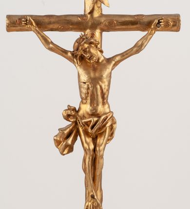 Zdjęcie nr 17: Grupa Ukrzyżowania umieszczona jest na wysokim cokole z ryzalitem pośrodku, profilowanym u dołu i zakończonym gzymsem z kostkowaniem. Do cokołu z trzech stron przytwierdzone są gwoździkami płaskorzeźbione narzędzia Męki Pańskiej. Grupa ustawiona jest na rzeźbionym podłożu imitującym skałę. Pośrodku znajduje się krzyż z pnia drzewa, do którego przybita jest trzema gwoździami figurka umarłego Chrystusa. Jego ciało jest w dużym zwisie, o ramionach przyjmujących kształt łuku półkolistego, głowa opada na prawy bark, nogi ułożone są równolegle, stopy skrzyżowane w układzie prawa na lewą. Twarz pociągła, okolona krótką brodą oraz silnie kręconymi włosami, na głowie korona cierniowa. Ciało smukłe, z podkreślonymi żebrami klatki piersiowej i zaznaczonymi śladami męki. Biodra przepasane krótkim, ekspresyjnie drapowanym perizonium, zawieszonym na podwójnym sznurze, odsłaniającym prawe biodro, zawiązanym na prawym boku. Pionowa belka krzyża zakończona banderolą z rytym napisem „IN / RI”. U podstawy krzyża znajduje się czaszka z piszczelami. 
Po prawej stronie krzyża stoi Maria ze splecionymi z przodu dłońmi. Ubrana jest w tunikę, przepasaną w talii oraz płaszcz narzucony na głowę i ramiona. Po lewej stronie znajduje się św. Jan. Zwrócony jest w trzech czwartych w prawo, klęczy na prawym kolanie i prawą dłoń kładzie na piersi, lewą rękę wyciąga do przodu. Jego twarz okalają długie włosy opadające na ramiona. Ubrany jest w tunikę, przepasaną w talii. 
Figury oraz detale rzeźbiarskie i profile cokołu pozłocone, struktura cokołu polichromowana na czarno. 