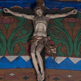 Zdjęcie nr 1: Figura umarłego Chrystusa przybita jest do krzyża o prostych ramionach czterema gwoździami. Ciało w lekkim zwisie o horyzontalnie rozłożonych ramionach, głowa bezwładnie opada na prawe ramię, nogi ugięte w kolanach, skierowane w prawo. Twarz Chrystusa jest pociągła, o zamkniętych oczach, prostym, długim nosie oraz pełnych, rozchylonych ustach, okolona krótką brodą oraz delikatnie kręconymi włosami opadającymi na prawe ramię. Na głowie ma koronę cierniową. Ciało wychudzone, o silnie zaznaczonej muskulaturze rąk i nóg, wyraźnie podkreślonych żebrach klatki piersiowej i zapadłym brzuchu. Biodra przepasane są krótkim perizonium zawieszonym na sznurze, z rozwianym zwisem tkaniny przy lewym boku. Polichromia ciała naturalistyczna z zaznaczonymi śladami męki, korona cierniowa i perizonium pozłocone. 


