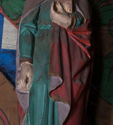 Zdjęcie nr 1: Figura ścięta z tyłu, ustawiona na podstawie w formie ściętej kuli. Święty ukazany frontalnie, w kontrapoście, z głową przechyloną na lewe ramię, prawą rękę ma opuszczoną wzdłuż ciała, lewą przytrzymuje przy piersi księgę. Twarz ma owalną o pełnych policzkach, małych, migdałowatych oczach, prostym nosie, pełnych ustach i wystającej brodzie. Włosy delikatnie kręcone, sięgające ramion. Ubrany jest w zieloną tunikę, przepasaną w talii oraz czerwony płaszcz, o różowej podszewce i złoconej lamówce, zapięty pod szyją, opadający na ramiona. Polichromia ciała naturalistyczna. 


