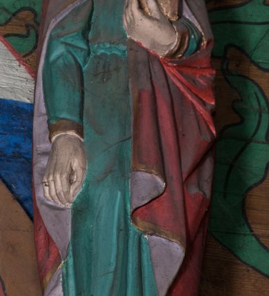 Zdjęcie nr 2: Figura ścięta z tyłu, ustawiona na podstawie w formie ściętej kuli. Święty ukazany frontalnie, w kontrapoście, z głową przechyloną na lewe ramię, prawą rękę ma opuszczoną wzdłuż ciała, lewą przytrzymuje przy piersi księgę. Twarz ma owalną o pełnych policzkach, małych, migdałowatych oczach, prostym nosie, pełnych ustach i wystającej brodzie. Włosy delikatnie kręcone, sięgające ramion. Ubrany jest w zieloną tunikę, przepasaną w talii oraz czerwony płaszcz, o różowej podszewce i złoconej lamówce, zapięty pod szyją, opadający na ramiona. Polichromia ciała naturalistyczna. 


