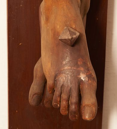 Zdjęcie nr 4: Rzeźbiona figura Chrystusa Ukrzyżowanego zawieszona na prostym, późniejszym od rzeźby krzyżu. Chrustu wisi z rozłożonymi do boków rękami przybitymi gwoździami, ze stopami złożonymi razem, prawa na lewej, przybitymi jednym gwoździem; kolana lekko ugięte. Ciało wyprężone, z zaznaczonymi żebrami i muskulaturą. Głowa opada na prawe ramię, twarz pociągła, oczy przymknięte, proste, nos prosty, długi, usta rozchylone, otoczone krótkimi wąsami i dzieląca się w dwa pukle brodą. Długie, kręcone włosy opadają do przodu, na tors, na głowie masywna, złocona korona cierniowa. Figura bejcowana na kolor ciemnobrązowy. Biodra przewiązane srebrzonym, krótkim perizonium którego zwoje przeplatają się z przodu, a koniec przy prawym udzie zawija się w ekspresyjny zwój. Tkanina układa się w drobne fałdy. Chrystus wisi na drewnianym, ciemnobrązowym krzyżu, w jej górnej części titulus z napisem „I.N./R.I.”.  