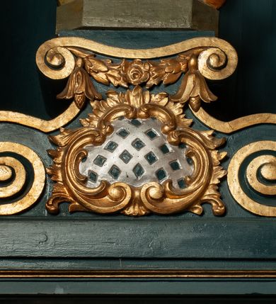 Zdjęcie nr 3: Rzeźba pełnoplastyczna przedstawia św. Kazimierza Królewicza. Święty ukazany jest w pozycji stojącej na niskim cokole, frontalnie, z lewą nogą wysuniętą do przodu. W prawej dłoni trzyma złote berło, lewą ma złożoną na piersi. Twarz podłużna o młodzieńczych rysach, z wyraźnie zaznaczonym podbródkiem, wzrokiem skierowanym przed siebie, okolona długimi i jasnymi włosami, spływającymi równolegle po bokach i symetrycznie podwiniętymi na końcach. Ubrany jest w strój książęcy: długą i białą suknię, obszytą futrem sobolowym, dekorowaną złotymi gwiazdami oraz ciemnoczerwony płaszcz zdobiony wicią akantową z zieloną podszewką, przerzucony swobodnie przez lewe ramię. Na głowie mitra książęca, na stopach buty z wysokimi cholewami, u lewego boku zawieszony na pasie miecz. Polichromia w odsłoniętych partiach ciała naturalistyczna, jasna; berło i detale złocone.

