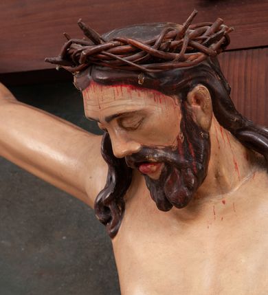 Zdjęcie nr 2: Pełnoplastyczna figura Chrystusa na prostym krzyżu umieszczona na tle malowanego przedstawienia grupy Ukrzyżowania z Marią, św. Janem i z Jerozolimą pośrodku. Rzeźba Chrystusa przybita do krzyża trzema gwoździami, ukazana w typie Cristo morto. Ciało w delikatnym zwisie, sylwetka wydłużona o delikatnie podkreślonej anatomii, nogi lekko ugięte w kolanach. Chrystus ma głowę przechyloną na prawe ramię. Twarz szczupła, z wąskim i długim nosem, zamkniętymi oczami, na wpół otwartymi ustami, okolona krótką brodą, rozdzieloną na końcu w dwa pukle. Włosy długie, spływające na ramiona dwoma skręconymi lokami, na głowie założona korona cierniowa. Perizonium zawiązane na węzeł na prawym boku, z jednym końcem zwisającym wzdłuż prawej nogi, z przodu tworzące fałdy na kształt litery „V”. Z boku, dłoni, stóp i spod korony cierniowej spływają strużki krwi. Polichromia ciała naturalistyczna, perizonium i titulus złocone. Krzyż gładki, nad głową Chrystusa titulus w formie pionowej banderoli z napisem „I.N./R.I.”. 
