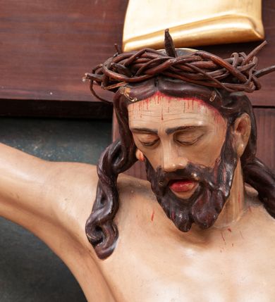 Zdjęcie nr 6: Pełnoplastyczna figura Chrystusa na prostym krzyżu umieszczona na tle malowanego przedstawienia grupy Ukrzyżowania z Marią, św. Janem i z Jerozolimą pośrodku. Rzeźba Chrystusa przybita do krzyża trzema gwoździami, ukazana w typie Cristo morto. Ciało w delikatnym zwisie, sylwetka wydłużona o delikatnie podkreślonej anatomii, nogi lekko ugięte w kolanach. Chrystus ma głowę przechyloną na prawe ramię. Twarz szczupła, z wąskim i długim nosem, zamkniętymi oczami, na wpół otwartymi ustami, okolona krótką brodą, rozdzieloną na końcu w dwa pukle. Włosy długie, spływające na ramiona dwoma skręconymi lokami, na głowie założona korona cierniowa. Perizonium zawiązane na węzeł na prawym boku, z jednym końcem zwisającym wzdłuż prawej nogi, z przodu tworzące fałdy na kształt litery „V”. Z boku, dłoni, stóp i spod korony cierniowej spływają strużki krwi. Polichromia ciała naturalistyczna, perizonium i titulus złocone. Krzyż gładki, nad głową Chrystusa titulus w formie pionowej banderoli z napisem „I.N./R.I.”. 
