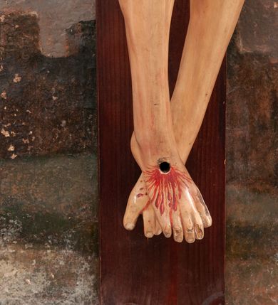 Zdjęcie nr 8: Pełnoplastyczna figura Chrystusa na prostym krzyżu umieszczona na tle malowanego przedstawienia grupy Ukrzyżowania z Marią, św. Janem i z Jerozolimą pośrodku. Rzeźba Chrystusa przybita do krzyża trzema gwoździami, ukazana w typie Cristo morto. Ciało w delikatnym zwisie, sylwetka wydłużona o delikatnie podkreślonej anatomii, nogi lekko ugięte w kolanach. Chrystus ma głowę przechyloną na prawe ramię. Twarz szczupła, z wąskim i długim nosem, zamkniętymi oczami, na wpół otwartymi ustami, okolona krótką brodą, rozdzieloną na końcu w dwa pukle. Włosy długie, spływające na ramiona dwoma skręconymi lokami, na głowie założona korona cierniowa. Perizonium zawiązane na węzeł na prawym boku, z jednym końcem zwisającym wzdłuż prawej nogi, z przodu tworzące fałdy na kształt litery „V”. Z boku, dłoni, stóp i spod korony cierniowej spływają strużki krwi. Polichromia ciała naturalistyczna, perizonium i titulus złocone. Krzyż gładki, nad głową Chrystusa titulus w formie pionowej banderoli z napisem „I.N./R.I.”. 
