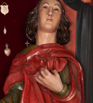 Zdjęcie nr 3: Pełnoplastyczna, polichromowana figura św. Jana ustawiona na niewielkim cokole. Święty ukazany w delikatnym kontrapoście z lewą nogą ugiętą w kolanie, głową uniesioną do góry. Prawą rękę ma wyciągniętą w bok, lewą złożoną na piersi podtrzymuje udrapowaną połę płaszcza. Święty o młodzieńczej fizjonomii, z długimi rozwianymi włosami skręcającymi się w bujne loki po bokach. Twarz pozbawiona zarostu, oczy skierowane ku górze, półkoliste łuki brwiowe. Ubrany jest  w długą, zieloną suknię opadającą prostymi fałdami oraz czerwony płaszcz zarzucony na ramiona, udrapowany na piersi, zawinięty pod lewą ręką. Spod szat wystają bose stopy. Polichromia w odsłoniętych partiach ciała naturalistyczna.