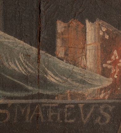 Zdjęcie nr 4: Obraz w formie stojącego prostokąta. Po prawej stronie św. Mateusz przedstawiony w półpostaci, zwrócony w trzech czwartych w lewo, z głową skierowaną w przeciwną stronę. Święty siedzi przy stole, na którym stoi kałamarz, lewą ręką podtrzymuje otwartą księgę, prawą pisze w niej piórem. Ma pociągłą twarz z wysokim czołem, o starczych rysach, migdałowatych oczach, prostym nosie i pełnych ustach, okoloną długą, siwą, rozdwajającą się brodą oraz krótkimi, białymi włosami, zaczesanymi do tyłu. Ubrany jest w ciemną tunikę z podwiniętym rękawem oraz jasnoczerwony płaszcz przerzucony przez lewe ramię i opadający na kolana. Za św. Mateuszem stoi anioł, widoczny z lewej strony kompozycji, obejmując go lewym ramieniem, prawą dłonią zaś wskazuje na księgę. Prawe skrzydło ma złożone, lewe rozłożone, wyciągnięte w bok. Anioł ma pociągłą twarz, o półprzymkniętych oczach, prostym nosie i pełnych ustach, okoloną brązowymi włosami sięgającymi ramion. Ubrany jest w pomarańczowo-różową tunikę, przepasaną w talii. Scena ukazana jest we wnętrzu, z oknem w górnym lewym rogu obrazu. Pod półką na książki w prawej części obrazu znajduje się napis: „S(ANCTUS) MATHEUS”. Rama czarna, dekorowana złoconym ornamentem roślinnym.