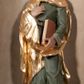 Zdjęcie nr 1: Rzeźba drążona, postać umieszczona na cokole. Święty Jan Ewangelista ukazany w całej postaci, frontalnie, prawą rękę przyciska do piersi w lewej opuszczonej wzdłuż ciała trzyma zamkniętą księgę. Twarz pociągła, o pełnych policzkach z długim nosem, małymi ustami oraz jasnoniebieskimi oczami, okolona krótkimi brązowymi włosami układającymi się w pukle. Święty jest ubrany w zieloną tunikę z wąskimi rękawami opadającą do podstawy płytkimi, miękkimi fałdami oraz złoty płaszcz spięty na dekolcie, zarzucony na ramiona, podtrzymywany z przodu przez prawe przedramię. Obok bosych stóp świętego, po jego prawej stronie ukazany biały orzeł z rozpostartymi skrzydłami.
