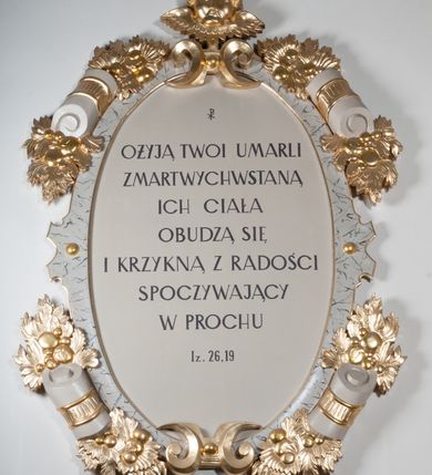 Zdjęcie nr 4: Rzeźba drążona, postać umieszczona na cokole przedstawiająca św. Marka Ewangelistę. Święty ukazany jest w pozycji stojącej, w kontrapoście, z lewą nogą zgiętą w kolanie i sylwetką przechyloną nieznacznie na lewą stronę, a głową odwróconą w przeciwnym kierunku. Prawa ręka wyprostowana, wyciągnięta przed siebie, lewa ugięta, podtrzymuje otwartą księgę. Święty ma pociągłą twarz o okrągłych, szeroko otwartych, niebieskich oczach, długim, wąskim nosie i małych ustach, okoloną zwiniętymi w pukle włosami zakrywającymi uszy oraz od dołu silnie poskręcaną brodę. Ubrany jest w brązową suknię z podwiniętymi rękawami opadającą do stóp podkreślającymi anatomię fałdami oraz w złoty płaszcz przechodzący przez lewy bark i zarzucony na prawe przedramię, układający się w nieregularne, głębokie fałdy. Stopy bose. Przy prawej nodze świętego lew. 