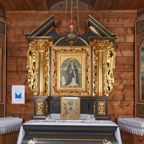 Zdjęcie nr 1: Nastawa architektoniczna, jednoosiowa, jednokondygnacyjna. Ołtarz drewniany, sarkofagowy z drewnianą mensą, od frontu dekorowany malowanym na złoto medalionem złożonym z czterech spiętych kabłąkami wolutek. Całość obwiedziona malowaną w kolorze złotym, cienką ramką z wolutkami w narożach. Na mensie ustawione jest nowe tabernakulum w formie prostopadłościennej skrzynki. Ścianki tabernakulum ujęte są złoconymi listewkami, zdobionymi wicią roślinną; drzwiczki w kształcie stojącego prostokąta z płaskorzeźbionym przedstawieniem kielicha z hostią w polu oraz winnym gronem i kłosami zboża po bokach na srebrnym tle. Nastawa ustawiona na cokole, ujęta parą złoconych, gładkich kolumn, dźwigających przerwane belkowanie. Kolumny ustawione są na cokołach wysuniętych przed lico ołtarza, za nimi dekoracja małżowinowo-chrząstkowa, kapitele kompozytowe. Cokoły zdobione są prostokątnymi płycinami zdobionymi na ściankach bocznych ornamentem małżowinowo-chrząstkowym, a na ściankach frontowych główkami aniołków na tle ornamentu. Twarze aniołków o pucułowatych policzkach i bujnych włosach, skierowane na wprost, z chustami pod szyją. W predelli znajduje się płycina w kształcie leżącego prostokąta o półkoliście zakończonych bokach. W polu środkowym nastawy obraz św. Otylii w formie stojącego prostokąta ujęty szeroką ramą, zdobioną ornamentem małżowinowo-chrząstkowym. Całość zamknięta jest przerywanym trójkątnym przyczółkiem. Pośrodku przyczółka pole zamknięte łukiem półkolistym. Kondygnacja ujęta jest po bokach uszami z ornamentu małżowinowo-chrząstkowego. Struktura polichromowana na czarno, profilowania i ornamentyka złocone. 
