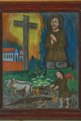 Zdjęcie nr 1: Obraz przedstawiający św. Izydora Oracza w kształcie stojącego prostokąta, podzielony na dwie strefy.  W dolnej strefie został ukazany anioł orzący pole za pomocą pary wołów i pługa. Anioł ubrany jest ciemnozieloną tunikę, ma również czerwone skrzydła. Powyżej ukazana jest niewielka scenka rodzajowa przedstawiająca pasterza, ubranego w strój krakowski: niebieską sukmanę i czerwony kapelusz, stado białych owieczek oraz latające wrony. W górnej strefie obrazu, po prawej stronie został ukazany św. Izydor, który klęczy przed przydrożnym krzyżem ze złożonymi w geście modlitwy rękami. Święty ubrany jest w brunatno-zieloną sukmanę, szare spodnie i czarne buty z wysokimi cholewami. Twarz z dużymi oczami, krótkim zarostem okolona długimi i brązowymi włosami. Wokół głowy ma trójstrefowy nimb: brązowy kolisty, niebieski okrągły i żółty utworzony z przerywanej kreski. Sylwetki postaci, draperie oraz brzegi szat oddane są konturem i wypełnione płaską plamą barwną. Po lewej stronie obrazu widoczne murowane zabudowania z jasnobrązowymi dachami. Krzyż prosty, a wokół jego ramion jest namalowana żółto-pomarańczowa poświata. Tło obrazu jednolite, niebieskie. Rama drewniana, prosta, pokryta bejcą. 
