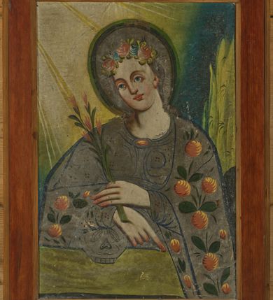 Zdjęcie nr 1: Obraz w kształcie pionowego prostokąta z przedstawieniem św. Rozalii. W centrum kompozycji święta została ukazana w półpostaci z głową delikatnie przechyloną na prawe ramię. Święta ma ręce ugięte w łokciach, skrzyżowane na wysokości talii, prawą wspiera na czaszce, a w lewej trzyma gałązkę z pękami różowych kwiatów lilii. Palec wskazujący prawej ręki ma wyprostowany, skierowany w kierunku prawego, dolnego naroża obrazu. Ubrana jest w szarą suknię oraz szary płaszcz zdobiony pomarańczowymi kolistymi kwiatami z zielonymi listkami. Szaty zdobione są konturowaną niebieską kreską oraz drobnymi kwiatkami w kształcie czterech bordowych kropek. Twarz pełna o jasnej karnacji z szerokim nosem, niebieskimi oczami, czerwonymi ustami i wysokim czołem. Włosy długie, ciemnobrązowe, opadające na plecy. Na głowie święta ma złożony wianek z czerwonych i niebieskich róż, a wokół niej szary nimb, okolony zielono-czarnym konturem. W lewym dolnym narożu obrazu znajduje się sumarycznie ukazana skała, na której leży czaszka. Tło o intensywnych barwach, po prawej stronie ciemnoniebieskie z wysoką żółtą trawą, natomiast po prawej stronie rozświetlone na żółto wychodzącymi z lewego górnego naroża obrazu promieniami. Ramą prosta, drewniana, bejcowana. 