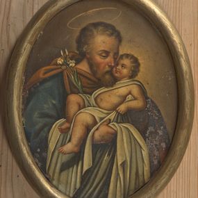 Zdjęcie nr 1: Obraz w kształcie owalu przedstawiający św. Józefa z Dzieciątkiem. Święty został ukazany w popiersiu, delikatnie zwrócony w lewo. Na rękach trzyma Dzieciątko Jezus oraz gałązkę białej lilii, która opiera się o jego prawe ramię. Święty ubrany jest w niebieską szatę z długimi rękawami oraz brązowy płaszcz spięty na prawym ramieniu broszą. Ma podłużną twarz okoloną krótką brodą, jasnobrązowe i kędzierzawe włosy, długi i wąski nos oraz delikatnie przymknięte oczy ze wzrokiem wpatrzonym w Jezusa. Dzieciątko ułożone jest w pozycji półleżącej na lewym ręku św. Józefa z uniesioną prawą nóżką i lewą rączką ugiętą w łokciu. Jezus ubrany jest w jasną pieluszkę, odsłaniającą lewą rączkę oraz tors i obficie spływającą w dół. Ma twarz o rysach niemowlęcych z pulchnymi i zarumienionymi policzkami. Wokół głowy Dzieciątka namalowany jest delikatny i promienisty nimb, a nad głową św. Józefa znajduje się nimb okrągły. Całość ukazana jest na ugrowym tle. Rama drewniana, okrągła, złocona.
