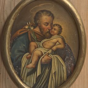 Zdjęcie nr 1: Obraz w kształcie owalu przedstawiający św. Józefa z Dzieciątkiem. Święty został ukazany w popiersiu, delikatnie zwrócony w lewo. Na rękach trzyma Dzieciątko Jezus oraz gałązkę białej lilii, która opiera się o jego prawe ramię. Święty ubrany jest w niebieską szatę z długimi rękawami oraz brązowy płaszcz spięty na prawym ramieniu broszą. Ma podłużną twarz okoloną krótką brodą, jasnobrązowe i kędzierzawe włosy, długi i wąski nos oraz delikatnie przymknięte oczy ze wzrokiem wpatrzonym w Jezusa. Dzieciątko ułożone jest w pozycji półleżącej na lewym ręku św. Józefa z uniesioną prawą nóżką i lewą rączką ugiętą w łokciu. Jezus ubrany jest w jasną pieluszkę, odsłaniającą lewą rączkę oraz tors i obficie spływającą w dół. Ma twarz o rysach niemowlęcych z pulchnymi i zarumienionymi policzkami. Wokół głowy Dzieciątka namalowany jest delikatny i promienisty nimb, a nad głową św. Józefa znajduje się nimb okrągły. Całość ukazana jest na ugrowym tle. Rama drewniana, okrągła, złocona.
