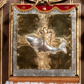 Zdjęcie nr 1: Tabernakulum proste, w formie prostopadłościennej skrzynki, o złotych drzwiczkach z wytłaczaną formą równoramiennego krzyża i wypukłą srebrną rybą oraz koszem z chlebem pośrodku. Po obu stronach, na niewysokich postumentach umieszczone dwa klęczące anioły z wysokimi, uniesionymi do góry skrzydłami, zwróconymi ku środkowi. Twarze o delikatnych rysach, silnie zarumienionych policzkach z 
długimi nosami, głęboko osadzonymi oczami i wysuniętym podbródkiem. Włosy długie, bujne, skręcone w duże pukle po bokach głowy. Anioły ubrane są w białe suknie i czerwone dalmatyki o fioletowych podszewkach. Anioł po lewej stronie trzyma w dłoniach kadzielnicę, a anioł po prawej płomienisty wazon. Polichromie w odsłoniętych partiach ciała naturalistyczne. 



