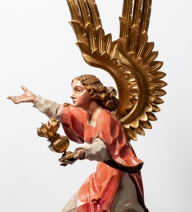 Zdjęcie nr 10: Tabernakulum proste, w formie prostopadłościennej skrzynki, o złotych drzwiczkach z wytłaczaną formą równoramiennego krzyża i wypukłą srebrną rybą oraz koszem z chlebem pośrodku. Po obu stronach, na niewysokich postumentach umieszczone dwa klęczące anioły z wysokimi, uniesionymi do góry skrzydłami, zwróconymi ku środkowi. Twarze o delikatnych rysach, silnie zarumienionych policzkach z 
długimi nosami, głęboko osadzonymi oczami i wysuniętym podbródkiem. Włosy długie, bujne, skręcone w duże pukle po bokach głowy. Anioły ubrane są w białe suknie i czerwone dalmatyki o fioletowych podszewkach. Anioł po lewej stronie trzyma w dłoniach kadzielnicę, a anioł po prawej płomienisty wazon. Polichromie w odsłoniętych partiach ciała naturalistyczne. 


