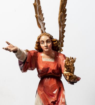 Zdjęcie nr 11: Tabernakulum proste, w formie prostopadłościennej skrzynki, o złotych drzwiczkach z wytłaczaną formą równoramiennego krzyża i wypukłą srebrną rybą oraz koszem z chlebem pośrodku. Po obu stronach, na niewysokich postumentach umieszczone dwa klęczące anioły z wysokimi, uniesionymi do góry skrzydłami, zwróconymi ku środkowi. Twarze o delikatnych rysach, silnie zarumienionych policzkach z 
długimi nosami, głęboko osadzonymi oczami i wysuniętym podbródkiem. Włosy długie, bujne, skręcone w duże pukle po bokach głowy. Anioły ubrane są w białe suknie i czerwone dalmatyki o fioletowych podszewkach. Anioł po lewej stronie trzyma w dłoniach kadzielnicę, a anioł po prawej płomienisty wazon. Polichromie w odsłoniętych partiach ciała naturalistyczne. 


