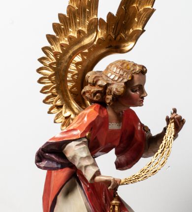 Zdjęcie nr 15: Tabernakulum proste, w formie prostopadłościennej skrzynki, o złotych drzwiczkach z wytłaczaną formą równoramiennego krzyża i wypukłą srebrną rybą oraz koszem z chlebem pośrodku. Po obu stronach, na niewysokich postumentach umieszczone dwa klęczące anioły z wysokimi, uniesionymi do góry skrzydłami, zwróconymi ku środkowi. Twarze o delikatnych rysach, silnie zarumienionych policzkach z 
długimi nosami, głęboko osadzonymi oczami i wysuniętym podbródkiem. Włosy długie, bujne, skręcone w duże pukle po bokach głowy. Anioły ubrane są w białe suknie i czerwone dalmatyki o fioletowych podszewkach. Anioł po lewej stronie trzyma w dłoniach kadzielnicę, a anioł po prawej płomienisty wazon. Polichromie w odsłoniętych partiach ciała naturalistyczne. 


