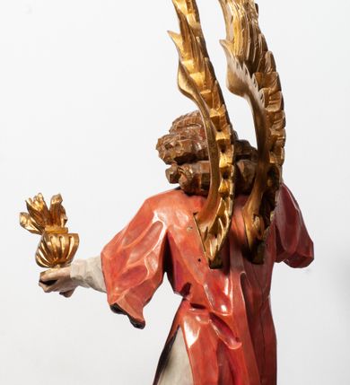 Zdjęcie nr 12: Tabernakulum proste, w formie prostopadłościennej skrzynki, o złotych drzwiczkach z wytłaczaną formą równoramiennego krzyża i wypukłą srebrną rybą oraz koszem z chlebem pośrodku. Po obu stronach, na niewysokich postumentach umieszczone dwa klęczące anioły z wysokimi, uniesionymi do góry skrzydłami, zwróconymi ku środkowi. Twarze o delikatnych rysach, silnie zarumienionych policzkach z 
długimi nosami, głęboko osadzonymi oczami i wysuniętym podbródkiem. Włosy długie, bujne, skręcone w duże pukle po bokach głowy. Anioły ubrane są w białe suknie i czerwone dalmatyki o fioletowych podszewkach. Anioł po lewej stronie trzyma w dłoniach kadzielnicę, a anioł po prawej płomienisty wazon. Polichromie w odsłoniętych partiach ciała naturalistyczne. 



