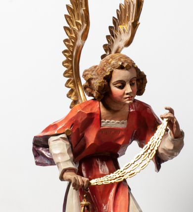 Zdjęcie nr 13: Tabernakulum proste, w formie prostopadłościennej skrzynki, o złotych drzwiczkach z wytłaczaną formą równoramiennego krzyża i wypukłą srebrną rybą oraz koszem z chlebem pośrodku. Po obu stronach, na niewysokich postumentach umieszczone dwa klęczące anioły z wysokimi, uniesionymi do góry skrzydłami, zwróconymi ku środkowi. Twarze o delikatnych rysach, silnie zarumienionych policzkach z 
długimi nosami, głęboko osadzonymi oczami i wysuniętym podbródkiem. Włosy długie, bujne, skręcone w duże pukle po bokach głowy. Anioły ubrane są w białe suknie i czerwone dalmatyki o fioletowych podszewkach. Anioł po lewej stronie trzyma w dłoniach kadzielnicę, a anioł po prawej płomienisty wazon. Polichromie w odsłoniętych partiach ciała naturalistyczne. 


