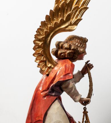 Zdjęcie nr 14: Tabernakulum proste, w formie prostopadłościennej skrzynki, o złotych drzwiczkach z wytłaczaną formą równoramiennego krzyża i wypukłą srebrną rybą oraz koszem z chlebem pośrodku. Po obu stronach, na niewysokich postumentach umieszczone dwa klęczące anioły z wysokimi, uniesionymi do góry skrzydłami, zwróconymi ku środkowi. Twarze o delikatnych rysach, silnie zarumienionych policzkach z 
długimi nosami, głęboko osadzonymi oczami i wysuniętym podbródkiem. Włosy długie, bujne, skręcone w duże pukle po bokach głowy. Anioły ubrane są w białe suknie i czerwone dalmatyki o fioletowych podszewkach. Anioł po lewej stronie trzyma w dłoniach kadzielnicę, a anioł po prawej płomienisty wazon. Polichromie w odsłoniętych partiach ciała naturalistyczne. 


