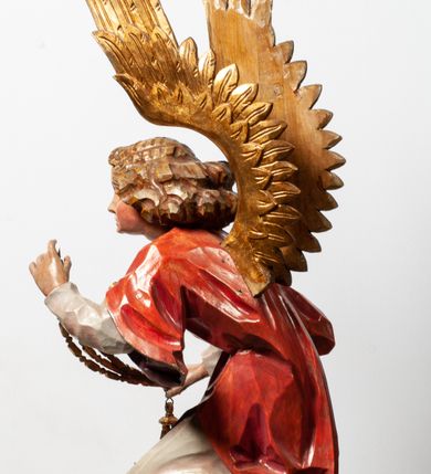 Zdjęcie nr 18: Tabernakulum proste, w formie prostopadłościennej skrzynki, o złotych drzwiczkach z wytłaczaną formą równoramiennego krzyża i wypukłą srebrną rybą oraz koszem z chlebem pośrodku. Po obu stronach, na niewysokich postumentach umieszczone dwa klęczące anioły z wysokimi, uniesionymi do góry skrzydłami, zwróconymi ku środkowi. Twarze o delikatnych rysach, silnie zarumienionych policzkach z 
długimi nosami, głęboko osadzonymi oczami i wysuniętym podbródkiem. Włosy długie, bujne, skręcone w duże pukle po bokach głowy. Anioły ubrane są w białe suknie i czerwone dalmatyki o fioletowych podszewkach. Anioł po lewej stronie trzyma w dłoniach kadzielnicę, a anioł po prawej płomienisty wazon. Polichromie w odsłoniętych partiach ciała naturalistyczne. 


