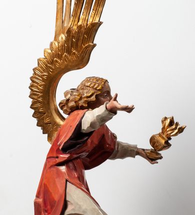 Zdjęcie nr 21: Tabernakulum proste, w formie prostopadłościennej skrzynki, o złotych drzwiczkach z wytłaczaną formą równoramiennego krzyża i wypukłą srebrną rybą oraz koszem z chlebem pośrodku. Po obu stronach, na niewysokich postumentach umieszczone dwa klęczące anioły z wysokimi, uniesionymi do góry skrzydłami, zwróconymi ku środkowi. Twarze o delikatnych rysach, silnie zarumienionych policzkach z 
długimi nosami, głęboko osadzonymi oczami i wysuniętym podbródkiem. Włosy długie, bujne, skręcone w duże pukle po bokach głowy. Anioły ubrane są w białe suknie i czerwone dalmatyki o fioletowych podszewkach. Anioł po lewej stronie trzyma w dłoniach kadzielnicę, a anioł po prawej płomienisty wazon. Polichromie w odsłoniętych partiach ciała naturalistyczne. 


