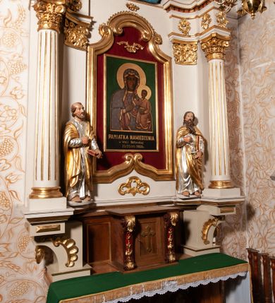 Zdjęcie nr 3: Nastawa ołtarzowa architektoniczna, jednokondygnacyjna ze zwieńczeniem. Ołtarz drewniany, flankowany dwoma filarami na niskich cokołach, pośrodku ażurowa, neogotycka krata; mensa drewniana. Tabernakulum w formie prostopadłościennej skrzynki, ustawione na niskim cokole, ujęte parą pilastrów w formie spływów wolutowych ozdobionych liśćmi akantu i kampanulami na trzonach. Na ściance przedniej drzwiczki w kształcie stojącego prostokąta. W polu w płycinie o analogicznym kształcie łaciński krzyżyk o trójlistnie zakończonych ramionach. Całość zamknięta profilowanym gzymsem. Po bokach tabernakulum stoją dwie figury klęczących aniołów. Nastawa ustawiona na wyłamanej pośrodku predelli, podtrzymującej podpory: parę kolumn o delikatnie zwężających się ku górze, kanelowanych trzonach z kompozytowymi pilastrami oraz wewnętrzną parę wklęsłych pilastrów o gładkich trzonach i stylizowanych kapitelach, wspierającymi przerwane nad osią główną belkowanie. W polu środkowym wnęka w kształcie stojącego prostokąta zamknięta od góry trzema wolutami, a od dołu fantazyjnie wycięta. Wewnątrz obraz Matki Boskiej Częstochowskiej. Poniżej, złotymi literami napis: „PAMIĄTKA NAWIEDZENIA / w Woli Batorskiej / 22/23.VIII.1968 r(oku)". Po lewej stronie ustawiona rzeźba św. Piotra, a po prawej św. Pawła. Zwieńczenie w formie owalu z płaskorzeźbionym przedstawieniem Najświętszego Serca Pana Jezusa, otoczone obłokami z trzema uskrzydlonymi główkami aniołków. Na szczycie zatknięty prosty, łaciński krzyżyk. Struktura polichromowana na kolor jasnobeżowy, detale i ornamentyka złocone i srebrzone.