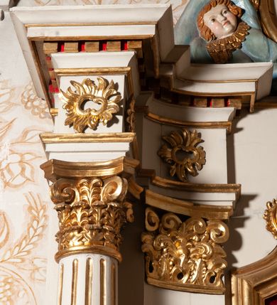 Zdjęcie nr 13: Nastawa ołtarzowa architektoniczna, jednokondygnacyjna ze zwieńczeniem. Ołtarz drewniany, flankowany dwoma filarami na niskich cokołach, pośrodku ażurowa, neogotycka krata; mensa drewniana. Tabernakulum w formie prostopadłościennej skrzynki, ustawione na niskim cokole, ujęte parą pilastrów w formie spływów wolutowych ozdobionych liśćmi akantu i kampanulami na trzonach. Na ściance przedniej drzwiczki w kształcie stojącego prostokąta. W polu w płycinie o analogicznym kształcie łaciński krzyżyk o trójlistnie zakończonych ramionach. Całość zamknięta profilowanym gzymsem. Po bokach tabernakulum stoją dwie figury klęczących aniołów. Nastawa ustawiona na wyłamanej pośrodku predelli, podtrzymującej podpory: parę kolumn o delikatnie zwężających się ku górze, kanelowanych trzonach z kompozytowymi pilastrami oraz wewnętrzną parę wklęsłych pilastrów o gładkich trzonach i stylizowanych kapitelach, wspierającymi przerwane nad osią główną belkowanie. W polu środkowym wnęka w kształcie stojącego prostokąta zamknięta od góry trzema wolutami, a od dołu fantazyjnie wycięta. Wewnątrz obraz Matki Boskiej Częstochowskiej. Poniżej, złotymi literami napis: „PAMIĄTKA NAWIEDZENIA / w Woli Batorskiej / 22/23.VIII.1968 r(oku)". Po lewej stronie ustawiona rzeźba św. Piotra, a po prawej św. Pawła. Zwieńczenie w formie owalu z płaskorzeźbionym przedstawieniem Najświętszego Serca Pana Jezusa, otoczone obłokami z trzema uskrzydlonymi główkami aniołków. Na szczycie zatknięty prosty, łaciński krzyżyk. Struktura polichromowana na kolor jasnobeżowy, detale i ornamentyka złocone i srebrzone.