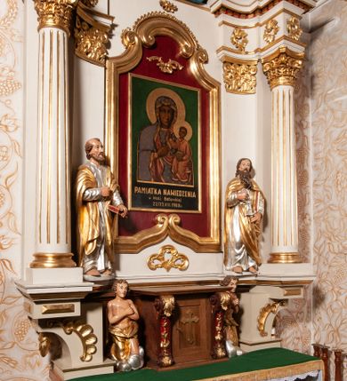 Zdjęcie nr 5: Nastawa ołtarzowa architektoniczna, jednokondygnacyjna ze zwieńczeniem. Ołtarz drewniany, flankowany dwoma filarami na niskich cokołach, pośrodku ażurowa, neogotycka krata; mensa drewniana. Tabernakulum w formie prostopadłościennej skrzynki, ustawione na niskim cokole, ujęte parą pilastrów w formie spływów wolutowych ozdobionych liśćmi akantu i kampanulami na trzonach. Na ściance przedniej drzwiczki w kształcie stojącego prostokąta. W polu w płycinie o analogicznym kształcie łaciński krzyżyk o trójlistnie zakończonych ramionach. Całość zamknięta profilowanym gzymsem. Po bokach tabernakulum stoją dwie figury klęczących aniołów. Nastawa ustawiona na wyłamanej pośrodku predelli, podtrzymującej podpory: parę kolumn o delikatnie zwężających się ku górze, kanelowanych trzonach z kompozytowymi pilastrami oraz wewnętrzną parę wklęsłych pilastrów o gładkich trzonach i stylizowanych kapitelach, wspierającymi przerwane nad osią główną belkowanie. W polu środkowym wnęka w kształcie stojącego prostokąta zamknięta od góry trzema wolutami, a od dołu fantazyjnie wycięta. Wewnątrz obraz Matki Boskiej Częstochowskiej. Poniżej, złotymi literami napis: „PAMIĄTKA NAWIEDZENIA / w Woli Batorskiej / 22/23.VIII.1968 r(oku)". Po lewej stronie ustawiona rzeźba św. Piotra, a po prawej św. Pawła. Zwieńczenie w formie owalu z płaskorzeźbionym przedstawieniem Najświętszego Serca Pana Jezusa, otoczone obłokami z trzema uskrzydlonymi główkami aniołków. Na szczycie zatknięty prosty, łaciński krzyżyk. Struktura polichromowana na kolor jasnobeżowy, detale i ornamentyka złocone i srebrzone.