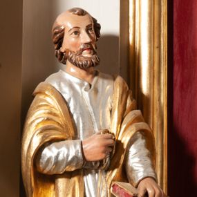 Zdjęcie nr 1: Rzeźba św. Piotra ustawiona na niskim cokole. Święty ukazany frontalnie z prawą ręką ugiętą w łokciu, w której na wysokości piersi trzyma klucz, w lewej opiera o biodro zamkniętą księgę. Twarz podłużna o szczupłych rysach z długim nosem i małymi oczami; średniej długości broda. Na głowie zaznaczona łysina z kępką włosów nad czołem i lokami zawiniętymi po bokach głowy. Ubrany jest w srebrzoną suknię i złocony płaszcz opadający z ramion. Polichromia w odsłoniętych partiach ciała naturalistyczna.
