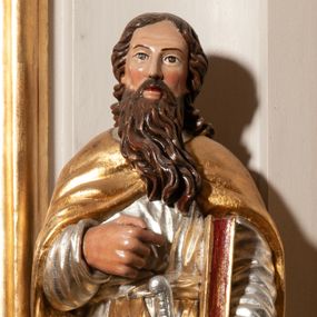 Zdjęcie nr 1: Święty Paweł ukazany całopostaciowo, frontalnie. W lewej dłoni trzyma miecz, ostrzem skierowany w dół, prawą ugiętą w łokciu, składa na piersi. Pod lewą ręką trzyma zamkniętą księgę. Twarz szeroka, nos długi, okolona długimi, pofalowanymi, brązowymi włosami i długą, brązową brodą. Ubrany jest w długą, srebrną suknię i złoty, pofałdowany, spięty na piersi płaszcz. Polichromia w odsłoniętych partiach ciała naturalistyczna, szaty i atrybuty złocone i srebrzone.