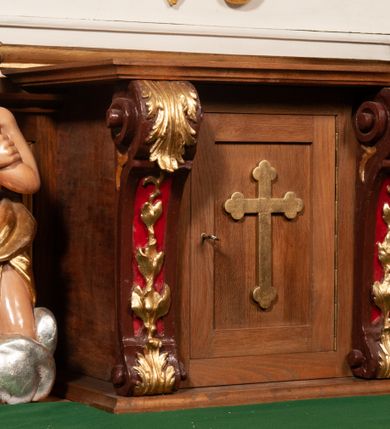 Zdjęcie nr 2: Tabernakulum w formie prostopadłościennej skrzynki, ustawione na niskim cokole, ujęte parą pilastrów w formie spływów wolutowych ozdobionych liśćmi akantu i kampanulami na trzonach. Na ściance przedniej drzwiczki w kształcie stojącego prostokąta. W polu w płycinie o analogicznym kształcie łaciński krzyżyk o trójlistnie zakończonych ramionach. Całość zamknięta profilowanym gzymsem. 