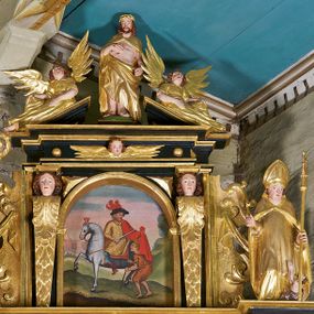 Zdjęcie nr 1: Obraz w kształcie stojącego prostokąta zamkniętego łukiem półkolistym. W centrum kompozycji ukazany św. Marcin siedzący na białym koniu. Ciało postaci zwrócone w trzech czwartych w prawo, tułów i głowa w trzech czwartych w lewo, w kierunku ubogiego przedstawionego z prawej strony obrazu. Święty Marcin został ukazany jako dojrzały mężczyzna o podłużnej twarzy z krótką, brązową brodą i wąsami w tym samym kolorze. Oczy skierowane do dołu, nos wydatny, prosty, usta niewielkie, zaznaczone czerwienią. W swojej prawej ręce święty trzyma miecz, którym odcina połę płaszcza, podtrzymywaną w lewym ręku. Ubrany jest w zapinany na torsie żółty kaftan z kołnierzem i długimi rękawami, wąskie, niebieskie spodnie oraz obszerny, czerwony płaszcz. Na głowie świętego ukazany czarny kapelusz z szerokim rondem ozdobiony trzema, czerwonymi piórami. Na nogach zaś brązowe buty z wysoką cholewką. Żebrak ukazany w pozycji stojącej, z lewego profilu. Ciało pochylone do przodu, wsparte na lasce, nogi ugięte w kolanach. Postać została przedstawiona jako młody, jasnowłosy mężczyzna o twarzy pozbawionej zarostu. Ma duże, szeroko otwarte oczy ze wzrokiem uniesionym ku górze, krótki, prosty nos oraz rozchylone usta. Ręce ugięte w łokciach, trzymające długą laskę. Żebrak jest ubrany w krótką, jasnobrązową szatę. Scena została ukazana na tle rozległego pejzażu z widocznym na dalszym planie zarysem miasta (z lewej strony kompozycji) oraz roślinnością (z prawej). Kolorystka utrzymana w jasnych, intensywnych barwach. 