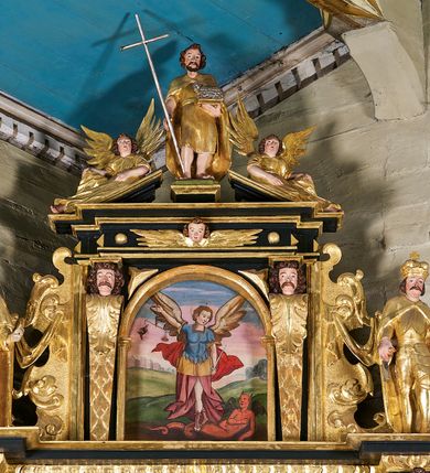 Zdjęcie nr 3: Ołtarz architektoniczny, jednoosiowy, jednokondygnacyjny ze zwieńczeniem, ujęty uszami z ornamentu małżowinowo-chrząstkowego oraz akantu. Mensa drewniana o linii wklęsło-wypukłej, z kamiennym portatylem, na odwrocie którego znajdują się napisy: „Anno D[omi]ni 1791 d(ie) 23 Julii Jllus[tr]ssimus R[evere]mdissimus D[ominus] Thimotheus / Nałęcz de Gorzen Gorzenski Ep[isco]pus Smolene(censis) hac Altare Portatile con/secravit et Reliquias s(acto)r)um) Laurentii [...] Martyr(um) imposui[t]”, „[...] et obsigillatum in actu visitationis ep[isco]palis / 29 Julii 1808 per Reverendissimum ec Illustri/ssimum D(omi)num Andre[am] Rawicz Gawtonski / Ep(isco)pu(m) Crac[oviensem] [...]”,  „Obsigillavimus / in visitazione canonica / die 29 Maii 1899/ + Joannes / princeps Ep(isco)p(us)” oraz „Obsigillavit Celsi(ssi)mus ac Rev(erendiss)mus / Adam Stephanus Princeps Sapieha / Princeps Arch(ie)p(isco)pus Cracoviensis in / actu visit(ationis) Can(once) / Wola Radziszowska die 25 Maii 1939 / Julianus Groblicki / secratarius.” Antepedium drewniane, w części centralnej dekorowane płaskorzeźbionym medalionem z wici roślinnej mieszczącym monogram IHS ujęty po bokach ornamentem roślinnym. Nastawa ustawiona na profilowanym cokole dekorowanym uskrzydlonymi główkami anielskimi. W części środkowej predella ze złoconą płyciną w kształcie leżącego prostokąta ujętego palmetami, wewnątrz której znajduje się obraz ze sceną Zwiastowania. Retabulum ujęte parą korynckich kolumn ustawionych na wysokich cokołach. Kolumny dźwigają odcinki wyłamanego belkowania zwieńczonego profilowanym gzymsem, na którym ustawiono figury św. Kazimierza i św. Floriana. Trzony kolumn złocone, w jednej trzeciej wysokości opięte profilowanym okuciem, poniżej którego płaskorzeźbione, uskrzydlone główki anielskie na tle ornamentu okuciowego, a powyżej winna latorośl na tle ornamentu okuciowego. Pole środkowe ołtarza w formie arkady zamkniętej łukiem półkolistym mieści obraz przedstawiający Ukrzyżowanie. W przyłuczach płaskorzeźbione, uskrzydlone główki anielskie. Zwieńczenie ujęte hermowymi pilastrami dźwigającymi niepełne, wyłamane belkowanie z uskrzydloną główką anielską na osi, na którym znajduje się trójkątny, przerwany przyczółek. Na ramionach przyczółka półleżące postaci aniołów, pomiędzy nimi, w osi ołtarza figura św. Jana Chrzciciela. W polu obraz w kształcie stojącego prostokąta zamkniętego łukiem półokrągłym przedstawiający św. Michała Archanioła. Zwieńczenie ujęte uszami utworzonymi z akantu oraz podwieszonej draperii. Struktura ołtarza jest polichromowana na ciemnozielono, ze złoconymi detalami architektonicznymi i ornamentyką. Figury w partiach ciała z naturalistyczną polichromią oraz złoconymi szatami i atrybutami.



