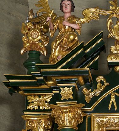 Zdjęcie nr 5: Ołtarz przyścienny, architektoniczny jednoosiowy i jednokondygnacyjny ze zwieńczeniem; ujęty akantowymi uszami. Mensa prostopadłościenna o linii wklęsło-wypukłej. Antepedium drewniane z umieszczonym centralnie medalionem utworzonym z wici roślinnej mieszczącym gorejące serce na tle skrzyżowanych kotwicy i krzyża. W dolnych narożach dodatkowo złocony akant. Tabernakulum srebrzone z wypukłymi drzwiczkami zamkniętymi półkoliście, na których umieszczony centralnie złocony kielich z hostią ujęty akantowymi wolutami. W górnej części drzwiczek uskrzydlona główka anielska. Nastawa umieszczona na wysokim cokole. Pole środkowe w formie stojącego prostokąta ujęte jest dwiema parami kolumn korynckich dźwigających niepełne belkowanie z silnie wysuniętym gzymsem i wyłamanym, przerwanym w partii środkowej trójkątnym przyczółkiem. Para kolumn wewnętrznych jest nieco wysunięta przed lico ołtarza. Cokoły kolumn dekorowane są płycinami wypełnionymi akantem. W polu środkowym ołtarza umieszczono profilowaną i złoconą ramę dekorowaną akantem ujętą płyciną zwieńczoną łukiem nadwieszonym. W ramie obraz Matki Boskiej z Dzieciątkiem w typie Hodegetrii. Ponad obrazem umieszczona jest złocona główka anielska z podwieszonymi girlandami. W partii fryzu rozety i ostrokrzew. W zwieńczeniu, na osi kolumn wewnętrznych znajduje się para aniołów siedzących na odcinkach przyczółka i trzymających liście akantu. Na osi kolumn zewnętrznych umieszczone wazony z kwiatami. W osi ołtarza akantowy kartusz z gołębicą Ducha Świętego na tle glorii promienistej na profilowanej podstawie. Całość zwieńczona jest figurą Boga Ojca z globem i otwartą księgą siedzącego pośród obłoków. Struktura ołtarza polichromowana jest na zielono ze złoconą ornamentyką i detalami architektonicznymi. Figury w partiach ciała polichromowane naturalistycznie, szaty i atrybuty złocone i srebrzone.