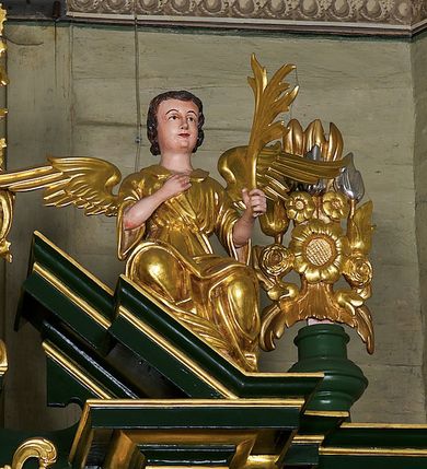 Zdjęcie nr 6: Ołtarz przyścienny, architektoniczny jednoosiowy i jednokondygnacyjny ze zwieńczeniem; ujęty akantowymi uszami. Mensa prostopadłościenna o linii wklęsło-wypukłej. Antepedium drewniane z umieszczonym centralnie medalionem utworzonym z wici roślinnej mieszczącym gorejące serce na tle skrzyżowanych kotwicy i krzyża. W dolnych narożach dodatkowo złocony akant. Tabernakulum srebrzone z wypukłymi drzwiczkami zamkniętymi półkoliście, na których umieszczony centralnie złocony kielich z hostią ujęty akantowymi wolutami. W górnej części drzwiczek uskrzydlona główka anielska. Nastawa umieszczona na wysokim cokole. Pole środkowe w formie stojącego prostokąta ujęte jest dwiema parami kolumn korynckich dźwigających niepełne belkowanie z silnie wysuniętym gzymsem i wyłamanym, przerwanym w partii środkowej trójkątnym przyczółkiem. Para kolumn wewnętrznych jest nieco wysunięta przed lico ołtarza. Cokoły kolumn dekorowane są płycinami wypełnionymi akantem. W polu środkowym ołtarza umieszczono profilowaną i złoconą ramę dekorowaną akantem ujętą płyciną zwieńczoną łukiem nadwieszonym. W ramie obraz Matki Boskiej z Dzieciątkiem w typie Hodegetrii. Ponad obrazem umieszczona jest złocona główka anielska z podwieszonymi girlandami. W partii fryzu rozety i ostrokrzew. W zwieńczeniu, na osi kolumn wewnętrznych znajduje się para aniołów siedzących na odcinkach przyczółka i trzymających liście akantu. Na osi kolumn zewnętrznych umieszczone wazony z kwiatami. W osi ołtarza akantowy kartusz z gołębicą Ducha Świętego na tle glorii promienistej na profilowanej podstawie. Całość zwieńczona jest figurą Boga Ojca z globem i otwartą księgą siedzącego pośród obłoków. Struktura ołtarza polichromowana jest na zielono ze złoconą ornamentyką i detalami architektonicznymi. Figury w partiach ciała polichromowane naturalistycznie, szaty i atrybuty złocone i srebrzone.