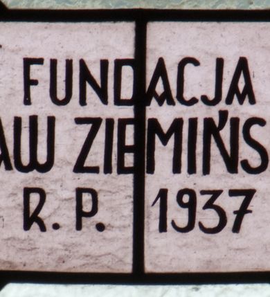 Zdjęcie nr 6: Witraż w kształcie stojącego prostokąta zamkniętego łukiem półkolistym. Kompozycja ujęta geometryczną bordiurą w kolorach czerwonym oraz jasno- i ciemnożółtym. Wewnątrz pole w kształcie stojącego prostokąta zamkniętego łukiem półkolistym z wpisanymi dwoma ostrołukami tworzącymi rodzaj gotyckiego biforium. W jego górnej części motyw kłosów oraz winnych gron. W polu z lewej strony kompozycji owalny medalion mieszczący przedstawienie św. Władysława w rycerskiej zbroi, zielonej tunice ze złotymi lamówkami i królewskim, czerwonym płaszczu z gronostajowym podbiciem umieszczone na tle pejzażu. Święty ukazany w tzw. długim popiersiu z ciałem zwróconym w trzech czwartych w prawo. Prawa ręka złożona na piersi, w lewej tarcza podzielona w słup, po prawej stronie białe i czerwone pasy, po lewej na srebrnym polu złoty krzyż z dwiema belkami. Na głowie hełm z koroną, wokół głowy nimb. Poniżej medalionu czerwona litera „A” w jasnożółtym polu w kształcie rombu oraz inskrypcja: „FUNDACJA / KS(IĄDZ) WŁADYSŁAW ZIEMIŃSKI PROBOSZCZ / R(OKU) P(AŃSKIEGO) 1937”. W polu z prawej strony kompozycji owalny medalion mieszczący scenę Nauczania Marii przez św. Annę umieszczoną na tle pejzażu. Święta Anna ukazana w pozycji siedzącej, z ciałem zwróconym w trzech czwartych w prawo, pochyla się ku stojącej po jej prawej stronie Marii. Lewa dłoń uniesiona w geście nauczania. Anna przedstawiona jako dojrzała kobieta ubrana w zieloną suknię, białą podwikę oraz czerwony płaszcz. Na głowie jasnozielona chusta. Maria ukazana z profilu w pozycji stojącej. Została przedstawiona jako kilkuletnia dziewczyna o długich, brązowych i falowanych włosach ujętych jasną opaską. Wokół głowy nimb. Ręce złożone w geście modlitwy. Postać ubrana jest w jasnoniebieską tunikę. Poniżej medaliony litera „Ω” w jasnożółtym polu w kształcie rombu oraz inskrypcja „FRANASOWA ANNA R(OKU) P(AŃSKIEGO) 1937”. 

