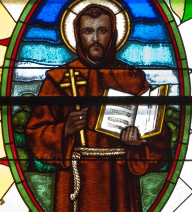 Zdjęcie nr 2: Witraż w kształcie stojącego prostokąta zamkniętego łukiem półkolistym. Kompozycja ujęta geometryczną bordiurą w kolorach czerwonym oraz jasno- i ciemnożółtym. Wewnątrz pole w kształcie stojącego prostokąta zamkniętego łukiem półkolistym z wpisanymi dwoma ostrołukami tworzącymi rodzaj gotyckiego biforium. W jego górnej części motyw kłosów oraz winnych gron. W polu z lewej strony kompozycji owalny medalion mieszczący przedstawienie św. Franciszka z Asyżu ubranego w brązowy habit przepasany sznurem, z kapturem na głowie, umieszczone na tle pejzażu. Święty ukazany frontalnie w tzw. długim popiersiu. W prawej ręce trzyma podwójny krzyż, w lewej otwartą księgę. Wokół głowy nimb. Poniżej medalionu godło tercjarzy (skrzyżowane ręce Chrystusa i św. Franciszka ze śladami po gwoździach w dłoniach, między którymi złoty krzyż na przecięciu ramion z koroną cierniową, u dołu błękitna wstęga) w jasnozielonym polu w kształcie rombu oraz inskrypcja „FUNDACJA / III ZAKON TERCJARZY R(OKU) P(AŃSKIEGO) 1937”. W polu z prawej strony kompozycji owalny medalion mieszczący wizerunek Matki Boskiej Śnieżnej na tle błękitnego nieba. Maria ukazana frontalnie, w tzw. długim popiersiu z głową zwróconą w trzech czwartych w lewo. Lewą ręką podtrzymuje Dzieciątko, prawa dłoń na tej samej wysokości z wyprostowanym palcem wskazującym i środkowym. Maria przedstawiona jako kobieta o owalnej twarzy z dużymi szeroko otwartymi oczami, prostym nosem i niewielkich, wąskich ustach. Jest ubrana w złote szaty – suknię z długimi rękawami oraz bogato zdobiony ornamentem roślinnym płaszcz. Na głowie złota chusta zdobiona ornamentem roślinnym oraz rozbudowana korona w typie zamkniętym zwieńczona krzyżem. Wokół głowy promienisty nimb. Dzieciątko przedstawione w pozycji siedzącej z ciałem zwróconym w trzech czwartych w kierunku Marii. Głowa uniesiona lekko do góry, prawa dłoń wyciągnięta do przodu wykonuje gest błogosławieństwa. W lewej dłoni Dzieciątko trzyma zamkniętą księgę. Postać jest ubrana w złotą tunikę z długimi rękawami zdobioną ornamentem roślinnym. Spod szat widoczne bose stopy. Na głowie Dzieciątka korona w typie zamkniętym zwieńczona krzyżem. Poniżej inskrypcja „FUNDACJA / RÓŻE MĘŻCZYZN I KOBIET R(OKU) P(AŃSKIEGO) 1937” oraz w prawym, dolnym rogu kompozycji sygnatura „Wy[konał] M[aksymilian] Romańczyk / Kraków”. Tło witraża wypełnia ukośna kratownica w kolorach jasnozielonym i białym (szkło bezbarwne).



