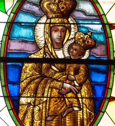 Zdjęcie nr 3: Witraż w kształcie stojącego prostokąta zamkniętego łukiem półkolistym. Kompozycja ujęta geometryczną bordiurą w kolorach czerwonym oraz jasno- i ciemnożółtym. Wewnątrz pole w kształcie stojącego prostokąta zamkniętego łukiem półkolistym z wpisanymi dwoma ostrołukami tworzącymi rodzaj gotyckiego biforium. W jego górnej części motyw kłosów oraz winnych gron. W polu z lewej strony kompozycji owalny medalion mieszczący przedstawienie św. Franciszka z Asyżu ubranego w brązowy habit przepasany sznurem, z kapturem na głowie, umieszczone na tle pejzażu. Święty ukazany frontalnie w tzw. długim popiersiu. W prawej ręce trzyma podwójny krzyż, w lewej otwartą księgę. Wokół głowy nimb. Poniżej medalionu godło tercjarzy (skrzyżowane ręce Chrystusa i św. Franciszka ze śladami po gwoździach w dłoniach, między którymi złoty krzyż na przecięciu ramion z koroną cierniową, u dołu błękitna wstęga) w jasnozielonym polu w kształcie rombu oraz inskrypcja „FUNDACJA / III ZAKON TERCJARZY R(OKU) P(AŃSKIEGO) 1937”. W polu z prawej strony kompozycji owalny medalion mieszczący wizerunek Matki Boskiej Śnieżnej na tle błękitnego nieba. Maria ukazana frontalnie, w tzw. długim popiersiu z głową zwróconą w trzech czwartych w lewo. Lewą ręką podtrzymuje Dzieciątko, prawa dłoń na tej samej wysokości z wyprostowanym palcem wskazującym i środkowym. Maria przedstawiona jako kobieta o owalnej twarzy z dużymi szeroko otwartymi oczami, prostym nosem i niewielkich, wąskich ustach. Jest ubrana w złote szaty – suknię z długimi rękawami oraz bogato zdobiony ornamentem roślinnym płaszcz. Na głowie złota chusta zdobiona ornamentem roślinnym oraz rozbudowana korona w typie zamkniętym zwieńczona krzyżem. Wokół głowy promienisty nimb. Dzieciątko przedstawione w pozycji siedzącej z ciałem zwróconym w trzech czwartych w kierunku Marii. Głowa uniesiona lekko do góry, prawa dłoń wyciągnięta do przodu wykonuje gest błogosławieństwa. W lewej dłoni Dzieciątko trzyma zamkniętą księgę. Postać jest ubrana w złotą tunikę z długimi rękawami zdobioną ornamentem roślinnym. Spod szat widoczne bose stopy. Na głowie Dzieciątka korona w typie zamkniętym zwieńczona krzyżem. Poniżej inskrypcja „FUNDACJA / RÓŻE MĘŻCZYZN I KOBIET R(OKU) P(AŃSKIEGO) 1937” oraz w prawym, dolnym rogu kompozycji sygnatura „Wy[konał] M[aksymilian] Romańczyk / Kraków”. Tło witraża wypełnia ukośna kratownica w kolorach jasnozielonym i białym (szkło bezbarwne).



