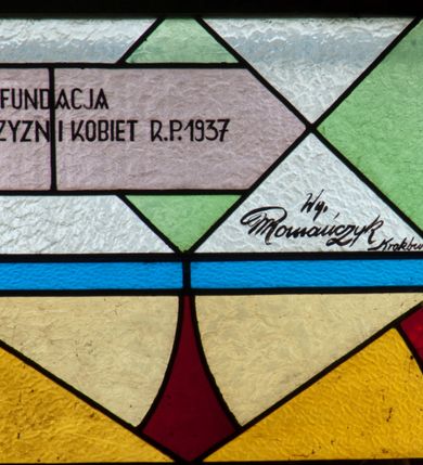 Zdjęcie nr 7: Witraż w kształcie stojącego prostokąta zamkniętego łukiem półkolistym. Kompozycja ujęta geometryczną bordiurą w kolorach czerwonym oraz jasno- i ciemnożółtym. Wewnątrz pole w kształcie stojącego prostokąta zamkniętego łukiem półkolistym z wpisanymi dwoma ostrołukami tworzącymi rodzaj gotyckiego biforium. W jego górnej części motyw kłosów oraz winnych gron. W polu z lewej strony kompozycji owalny medalion mieszczący przedstawienie św. Franciszka z Asyżu ubranego w brązowy habit przepasany sznurem, z kapturem na głowie, umieszczone na tle pejzażu. Święty ukazany frontalnie w tzw. długim popiersiu. W prawej ręce trzyma podwójny krzyż, w lewej otwartą księgę. Wokół głowy nimb. Poniżej medalionu godło tercjarzy (skrzyżowane ręce Chrystusa i św. Franciszka ze śladami po gwoździach w dłoniach, między którymi złoty krzyż na przecięciu ramion z koroną cierniową, u dołu błękitna wstęga) w jasnozielonym polu w kształcie rombu oraz inskrypcja „FUNDACJA / III ZAKON TERCJARZY R(OKU) P(AŃSKIEGO) 1937”. W polu z prawej strony kompozycji owalny medalion mieszczący wizerunek Matki Boskiej Śnieżnej na tle błękitnego nieba. Maria ukazana frontalnie, w tzw. długim popiersiu z głową zwróconą w trzech czwartych w lewo. Lewą ręką podtrzymuje Dzieciątko, prawa dłoń na tej samej wysokości z wyprostowanym palcem wskazującym i środkowym. Maria przedstawiona jako kobieta o owalnej twarzy z dużymi szeroko otwartymi oczami, prostym nosem i niewielkich, wąskich ustach. Jest ubrana w złote szaty – suknię z długimi rękawami oraz bogato zdobiony ornamentem roślinnym płaszcz. Na głowie złota chusta zdobiona ornamentem roślinnym oraz rozbudowana korona w typie zamkniętym zwieńczona krzyżem. Wokół głowy promienisty nimb. Dzieciątko przedstawione w pozycji siedzącej z ciałem zwróconym w trzech czwartych w kierunku Marii. Głowa uniesiona lekko do góry, prawa dłoń wyciągnięta do przodu wykonuje gest błogosławieństwa. W lewej dłoni Dzieciątko trzyma zamkniętą księgę. Postać jest ubrana w złotą tunikę z długimi rękawami zdobioną ornamentem roślinnym. Spod szat widoczne bose stopy. Na głowie Dzieciątka korona w typie zamkniętym zwieńczona krzyżem. Poniżej inskrypcja „FUNDACJA / RÓŻE MĘŻCZYZN I KOBIET R(OKU) P(AŃSKIEGO) 1937” oraz w prawym, dolnym rogu kompozycji sygnatura „Wy[konał] M[aksymilian] Romańczyk / Kraków”. Tło witraża wypełnia ukośna kratownica w kolorach jasnozielonym i białym (szkło bezbarwne).



