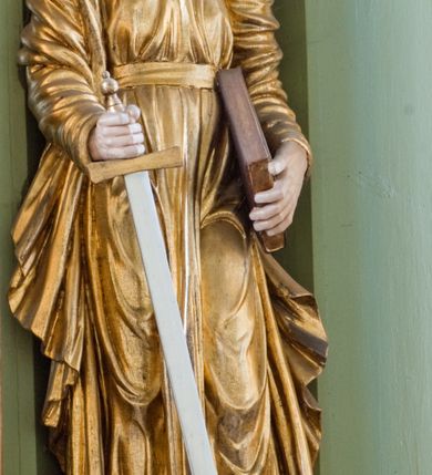 Zdjęcie nr 35: Ołtarz przyścienny, architektoniczny, trójosiowy, dwukondygnacyjny ze zwieńczeniem. Nastawa umieszczona na wysokim, dwudzielnym cokole w górnej części zdobionym na przemian dekoracją płycinową i motywem muszli palmetowej z podwieszoną girlandą kwiatową oraz rozetkami. Cokół wieńczy profilowany gzyms dekorowany kostkowaniem. Antepedium współczesne, marmurowe z umieszczonym centralnie prostym, równoramiennym krzyżem. Na mensie ustawione tabernakulum z tronem wystawienia, o formach architektonicznych, ujęte zdwojonymi, smukłymi kolumienkami o złoconych trzonach umieszczonymi na wysokich cokołach. Podpory dźwigają odcinki pełnego belkowania, na których ustawione złocone figury klęczących aniołów. Część centralna o linii wypukłej, dwukondygnacyjna. W kondygnacji pierwszej złocone drzwiczki z płaskorzeźbionym kielichem z hostią na tle glorii promienistej, powyżej, w kondygnacji drugiej tron wystawienia ujęty rzeźbioną, złoconą kotarą. W zwieńczeniu srebrzona figura baranka apokaliptycznego leżącego na księdze. Nastawa ujęta zdwojonymi, kompozytowymi kolumnami o złoconych trzonach i kapitelach. Pomiędzy kolumnami, w niszach rzeźbione figury św. Piotra (z lewej) i św. Pawła (z prawej), ponad którymi motyw symetrycznie podwieszonej kotary. Kolumny dźwigają odcinki pełnego belkowania z fryzem dekorowanym rozetkami i uskrzydlonymi główkami anielskimi oraz wydatnym gzymsem dekorowanym kostkowaniem. Na osi wewnętrznej pary komun dodatkowo ustawione odcinki półkolistego tympanonu, na których siedzą putta. W polu głównym ołtarza złocona, profilowana rama w kształcie stojącego prostokąta zamkniętego łukiem nadwieszonym mieszcząca barokowy obraz Matki Boskiej z Dzieciątkiem. Nieco powyżej, w osi ołtarza dwa putta unoszące złoconą koronę typu zamkniętego zwieńczoną krzyżem. Kondygnacja druga ujęta parą pilastrów o kompozytowych kapitelach oraz uszami w formie spływów wolutowych, na których siedzące putta. W polu złocona i profilowana rama w kształcie stojącego prostokąta mieszcząca obraz przedstawiający Trójcę Świętą. Całość ołtarza wieńczy profilowany gzyms dekorowany kostkowaniem i zamknięty niskim, trójkątnym przyczółkiem. W polu tympanonu uskrzydlona główka anielska. Struktura ołtarza polichromowana w kolorze jasnozielonym z elementami czerwieni i bieli. Detale architektoniczne, ornamenty oraz szaty postaci złocone.

