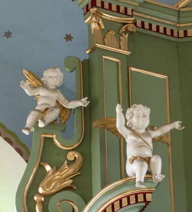 Zdjęcie nr 16: Ołtarz przyścienny, architektoniczny, trójosiowy, dwukondygnacyjny ze zwieńczeniem. Nastawa umieszczona na wysokim, dwudzielnym cokole w górnej części zdobionym na przemian dekoracją płycinową i motywem muszli palmetowej z podwieszoną girlandą kwiatową oraz rozetkami. Cokół wieńczy profilowany gzyms dekorowany kostkowaniem. Antepedium współczesne, marmurowe z umieszczonym centralnie prostym, równoramiennym krzyżem. Na mensie ustawione tabernakulum z tronem wystawienia, o formach architektonicznych, ujęte zdwojonymi, smukłymi kolumienkami o złoconych trzonach umieszczonymi na wysokich cokołach. Podpory dźwigają odcinki pełnego belkowania, na których ustawione złocone figury klęczących aniołów. Część centralna o linii wypukłej, dwukondygnacyjna. W kondygnacji pierwszej złocone drzwiczki z płaskorzeźbionym kielichem z hostią na tle glorii promienistej, powyżej, w kondygnacji drugiej tron wystawienia ujęty rzeźbioną, złoconą kotarą. W zwieńczeniu srebrzona figura baranka apokaliptycznego leżącego na księdze. Nastawa ujęta zdwojonymi, kompozytowymi kolumnami o złoconych trzonach i kapitelach. Pomiędzy kolumnami, w niszach rzeźbione figury św. Piotra (z lewej) i św. Pawła (z prawej), ponad którymi motyw symetrycznie podwieszonej kotary. Kolumny dźwigają odcinki pełnego belkowania z fryzem dekorowanym rozetkami i uskrzydlonymi główkami anielskimi oraz wydatnym gzymsem dekorowanym kostkowaniem. Na osi wewnętrznej pary komun dodatkowo ustawione odcinki półkolistego tympanonu, na których siedzą putta. W polu głównym ołtarza złocona, profilowana rama w kształcie stojącego prostokąta zamkniętego łukiem nadwieszonym mieszcząca barokowy obraz Matki Boskiej z Dzieciątkiem. Nieco powyżej, w osi ołtarza dwa putta unoszące złoconą koronę typu zamkniętego zwieńczoną krzyżem. Kondygnacja druga ujęta parą pilastrów o kompozytowych kapitelach oraz uszami w formie spływów wolutowych, na których siedzące putta. W polu złocona i profilowana rama w kształcie stojącego prostokąta mieszcząca obraz przedstawiający Trójcę Świętą. Całość ołtarza wieńczy profilowany gzyms dekorowany kostkowaniem i zamknięty niskim, trójkątnym przyczółkiem. W polu tympanonu uskrzydlona główka anielska. Struktura ołtarza polichromowana w kolorze jasnozielonym z elementami czerwieni i bieli. Detale architektoniczne, ornamenty oraz szaty postaci złocone.

