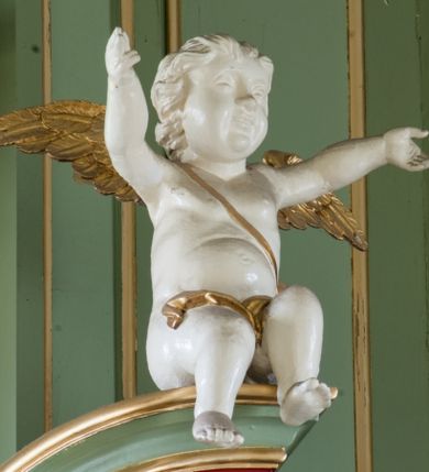 Zdjęcie nr 18: Ołtarz przyścienny, architektoniczny, trójosiowy, dwukondygnacyjny ze zwieńczeniem. Nastawa umieszczona na wysokim, dwudzielnym cokole w górnej części zdobionym na przemian dekoracją płycinową i motywem muszli palmetowej z podwieszoną girlandą kwiatową oraz rozetkami. Cokół wieńczy profilowany gzyms dekorowany kostkowaniem. Antepedium współczesne, marmurowe z umieszczonym centralnie prostym, równoramiennym krzyżem. Na mensie ustawione tabernakulum z tronem wystawienia, o formach architektonicznych, ujęte zdwojonymi, smukłymi kolumienkami o złoconych trzonach umieszczonymi na wysokich cokołach. Podpory dźwigają odcinki pełnego belkowania, na których ustawione złocone figury klęczących aniołów. Część centralna o linii wypukłej, dwukondygnacyjna. W kondygnacji pierwszej złocone drzwiczki z płaskorzeźbionym kielichem z hostią na tle glorii promienistej, powyżej, w kondygnacji drugiej tron wystawienia ujęty rzeźbioną, złoconą kotarą. W zwieńczeniu srebrzona figura baranka apokaliptycznego leżącego na księdze. Nastawa ujęta zdwojonymi, kompozytowymi kolumnami o złoconych trzonach i kapitelach. Pomiędzy kolumnami, w niszach rzeźbione figury św. Piotra (z lewej) i św. Pawła (z prawej), ponad którymi motyw symetrycznie podwieszonej kotary. Kolumny dźwigają odcinki pełnego belkowania z fryzem dekorowanym rozetkami i uskrzydlonymi główkami anielskimi oraz wydatnym gzymsem dekorowanym kostkowaniem. Na osi wewnętrznej pary komun dodatkowo ustawione odcinki półkolistego tympanonu, na których siedzą putta. W polu głównym ołtarza złocona, profilowana rama w kształcie stojącego prostokąta zamkniętego łukiem nadwieszonym mieszcząca barokowy obraz Matki Boskiej z Dzieciątkiem. Nieco powyżej, w osi ołtarza dwa putta unoszące złoconą koronę typu zamkniętego zwieńczoną krzyżem. Kondygnacja druga ujęta parą pilastrów o kompozytowych kapitelach oraz uszami w formie spływów wolutowych, na których siedzące putta. W polu złocona i profilowana rama w kształcie stojącego prostokąta mieszcząca obraz przedstawiający Trójcę Świętą. Całość ołtarza wieńczy profilowany gzyms dekorowany kostkowaniem i zamknięty niskim, trójkątnym przyczółkiem. W polu tympanonu uskrzydlona główka anielska. Struktura ołtarza polichromowana w kolorze jasnozielonym z elementami czerwieni i bieli. Detale architektoniczne, ornamenty oraz szaty postaci złocone.

