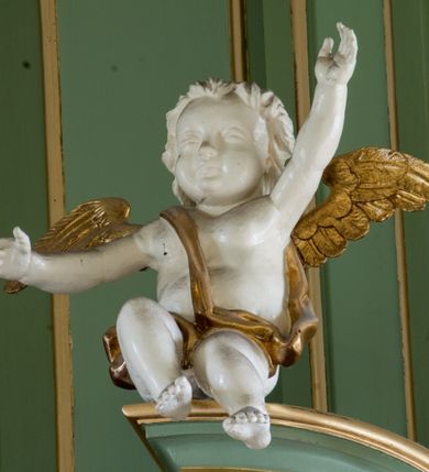 Zdjęcie nr 20: Ołtarz przyścienny, architektoniczny, trójosiowy, dwukondygnacyjny ze zwieńczeniem. Nastawa umieszczona na wysokim, dwudzielnym cokole w górnej części zdobionym na przemian dekoracją płycinową i motywem muszli palmetowej z podwieszoną girlandą kwiatową oraz rozetkami. Cokół wieńczy profilowany gzyms dekorowany kostkowaniem. Antepedium współczesne, marmurowe z umieszczonym centralnie prostym, równoramiennym krzyżem. Na mensie ustawione tabernakulum z tronem wystawienia, o formach architektonicznych, ujęte zdwojonymi, smukłymi kolumienkami o złoconych trzonach umieszczonymi na wysokich cokołach. Podpory dźwigają odcinki pełnego belkowania, na których ustawione złocone figury klęczących aniołów. Część centralna o linii wypukłej, dwukondygnacyjna. W kondygnacji pierwszej złocone drzwiczki z płaskorzeźbionym kielichem z hostią na tle glorii promienistej, powyżej, w kondygnacji drugiej tron wystawienia ujęty rzeźbioną, złoconą kotarą. W zwieńczeniu srebrzona figura baranka apokaliptycznego leżącego na księdze. Nastawa ujęta zdwojonymi, kompozytowymi kolumnami o złoconych trzonach i kapitelach. Pomiędzy kolumnami, w niszach rzeźbione figury św. Piotra (z lewej) i św. Pawła (z prawej), ponad którymi motyw symetrycznie podwieszonej kotary. Kolumny dźwigają odcinki pełnego belkowania z fryzem dekorowanym rozetkami i uskrzydlonymi główkami anielskimi oraz wydatnym gzymsem dekorowanym kostkowaniem. Na osi wewnętrznej pary komun dodatkowo ustawione odcinki półkolistego tympanonu, na których siedzą putta. W polu głównym ołtarza złocona, profilowana rama w kształcie stojącego prostokąta zamkniętego łukiem nadwieszonym mieszcząca barokowy obraz Matki Boskiej z Dzieciątkiem. Nieco powyżej, w osi ołtarza dwa putta unoszące złoconą koronę typu zamkniętego zwieńczoną krzyżem. Kondygnacja druga ujęta parą pilastrów o kompozytowych kapitelach oraz uszami w formie spływów wolutowych, na których siedzące putta. W polu złocona i profilowana rama w kształcie stojącego prostokąta mieszcząca obraz przedstawiający Trójcę Świętą. Całość ołtarza wieńczy profilowany gzyms dekorowany kostkowaniem i zamknięty niskim, trójkątnym przyczółkiem. W polu tympanonu uskrzydlona główka anielska. Struktura ołtarza polichromowana w kolorze jasnozielonym z elementami czerwieni i bieli. Detale architektoniczne, ornamenty oraz szaty postaci złocone.

