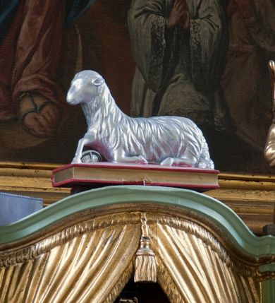 Zdjęcie nr 4: Tabernakulum z tronem wystawienia, jednokondycyjne o formach architektonicznych i wklęsło-wypukłym licu. Ujęte ustawionymi ukośnie, zdwojonymi, złoconymi kolumienkami wspartymi na wysokich cokołach. Kapitele kolumn kompozytowe, dźwigają odcinki pełnego belkowania wyłamanego w osiach podpór. Powyżej pełnoplastyczne, złocone figury klęczących aniołów. Drzwiczki tabernakulum złocone w kształcie stojącego prostokąta zamkniętego łukiem pełnym. Na licu płaskorzeźbiony kielich z hostią na tle glorii promienistej oraz kłosów zboża i winnych gron. Tron wystawienia o linii wypukłej z niszą ujętą płaskorzeźbioną, złoconą kotarą dekorowaną chwostami oraz muszlami palmetowymi. Tło wyłożone aksamitną, czerwoną tkaniną. W zwieńczeniu srebrzony Baranek Eucharystyczny spoczywający na księdze. Struktura tabernakulum malowana w odcieniu seledynowej zieleni, ornamentyka i załamania profili architektonicznych złocone.

