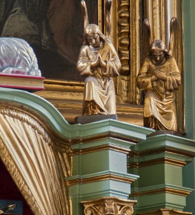 Zdjęcie nr 7: Tabernakulum z tronem wystawienia, jednokondycyjne o formach architektonicznych i wklęsło-wypukłym licu. Ujęte ustawionymi ukośnie, zdwojonymi, złoconymi kolumienkami wspartymi na wysokich cokołach. Kapitele kolumn kompozytowe, dźwigają odcinki pełnego belkowania wyłamanego w osiach podpór. Powyżej pełnoplastyczne, złocone figury klęczących aniołów. Drzwiczki tabernakulum złocone w kształcie stojącego prostokąta zamkniętego łukiem pełnym. Na licu płaskorzeźbiony kielich z hostią na tle glorii promienistej oraz kłosów zboża i winnych gron. Tron wystawienia o linii wypukłej z niszą ujętą płaskorzeźbioną, złoconą kotarą dekorowaną chwostami oraz muszlami palmetowymi. Tło wyłożone aksamitną, czerwoną tkaniną. W zwieńczeniu srebrzony Baranek Eucharystyczny spoczywający na księdze. Struktura tabernakulum malowana w odcieniu seledynowej zieleni, ornamentyka i załamania profili architektonicznych złocone.


