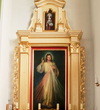 Zdjęcie nr 3: Ołtarz o formach architektonicznych, jednokondygnacyjny ze zwieńczeniem i akantowymi uszami wzbogaconymi o motywy kwiatowe. Mensa kamienna w formie stołu wspartego na dwóch filarach, umieszczona na dwustopniowym podwyższeniu. Na mensie prostopadłościenne tabernakulum ujęte złoconymi kolumienkami oraz zwieńczone złoconym, profilowanym gzymsem. Na drzwiczkach prostokątna płycina zwieńczona łukiem wklęsło-wypukłym. Nastawa drewniana ustawiona na cokole o dekoracji płycinowej, ujęta kanelowanymi pilastrami z kompozytowymi kapitelami z motywem podwieszonej kampanuli. W prostokątnym polu ołtarza obraz „Jezu Ufam Tobie” w złoconej i profilowanej ramie. Podpory dźwigają niepełne belkowanie z wydatnym gzymsem wyłamanym na osi pilastrów. Zwieńczenie prostokątne zamknięte profilowanym gzymsem o lini wklęsło-wypukłej, ujęte po bokach spływami wolutowymi. W polu zwieńczenia obraz w kształcie stojącego prostokąta zamkniętego łukiem wyniesionym mieszczący wizerunek św. Barbary. Całość ołtarza zwieńczona glorią promienistą z Okiem Opatrzności na czerwonym tle, ujętym medalionem utworzonym ze srebrzonych obłoków. Struktura ołtarza malowana w odcieniach beżu, detal ramy obrazu w polu głównym nastawy w kolorze czerwonym. Ornamentyka oraz załamania profili architektonicznych złocone.
